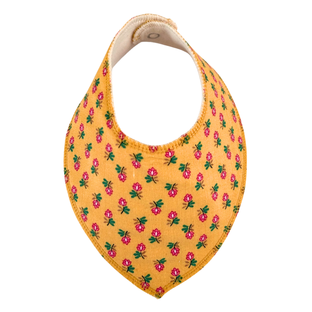 Dregglis sydd i gult tyg med blommr i rosa och grönt.