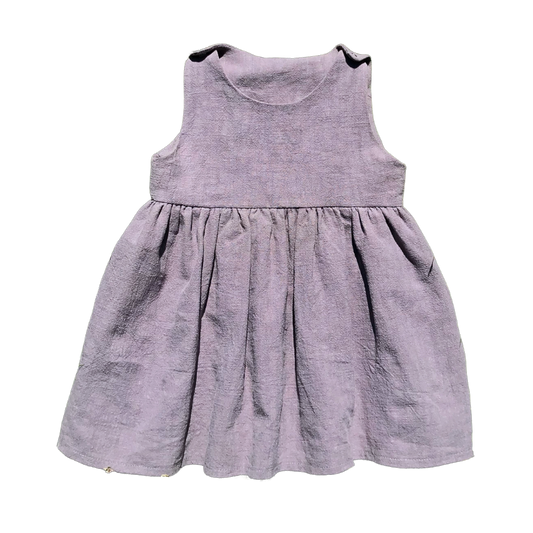 Barnklänning i återbrukat mellangrått linnetyg med rynkad kjol och tryckknappar på axlarna. Luftig, stilren och sydd i klassisk modell.